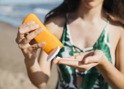Una mujer colocándose protector solar en la playa.