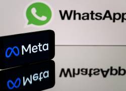 Esta fotografía muestra un teléfono inteligente y una pantalla de computadora que muestra los logotipos de la aplicación WhatsApp y su empresa matriz Meta.