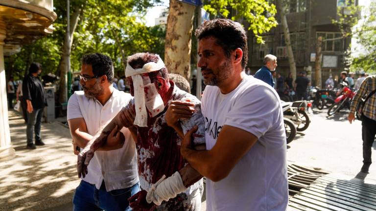 Iraníes atienden a un hombre que resultó herido en un supuesto ataque israelí en el bulevar Keshavarz, en el centro de Teherán, el 15 de junio de 2025.